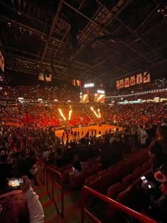 an indoor basketball game is being played in a stadium with people sitting on the bleachers