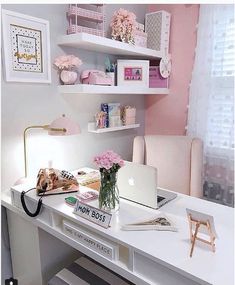 a white desk topped with a laptop computer next to a pink flower filled vase on top of it