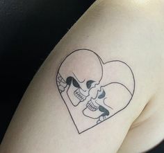 a woman's shoulder with a skull and heart tattoo on the left side of her arm