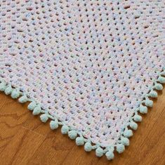 a crocheted baby blanket is laying on the floor