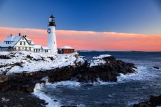 a light house sitting on top of a snow covered rocky cliff next to the ocean