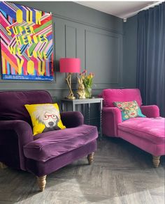 a living room with two purple chairs and a pink chair in front of a painting on the wall