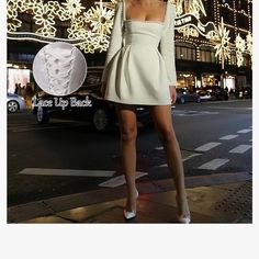 a woman standing on the side of a road in front of a christmas light display