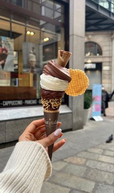 a person holding up an ice cream cone with waffles and chocolate on top