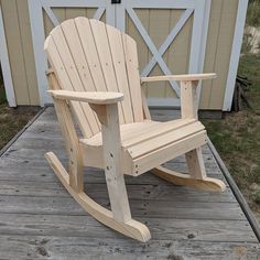 a wooden rocking chair sitting on top of a wooden deck next to a garage door