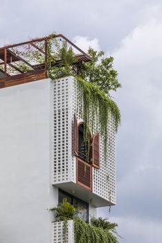 a tall white building with plants growing on it's windows and balconies