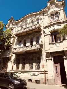 a car parked in front of an old building with balconies on the windows