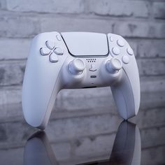 a white controller sitting on top of a table next to a brick wall and floor