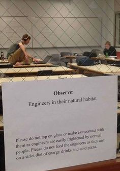 there is a sign on the table that says observe engineers in their natural habitat please do not tap on glass or make contact with them