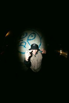 a man standing in front of a wall with graffiti on it