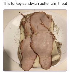 a white plate topped with sliced meat on top of a wooden table next to a knife and fork