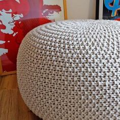 a large white knitted poufce sitting on top of a hard wood floor