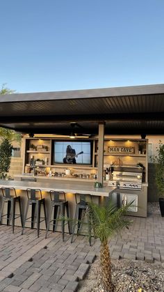 an outdoor bar with several stools and a television