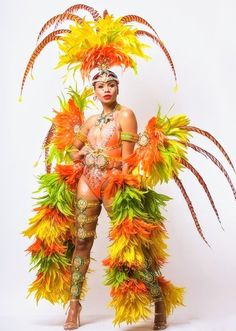 a woman in an orange and yellow costume with feathers on her head, standing against a white background