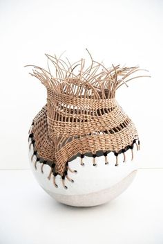 a white and brown vase with grass in it