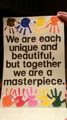 a person holding up a sign that says we are each unique and beautiful but together we are a masterpiece