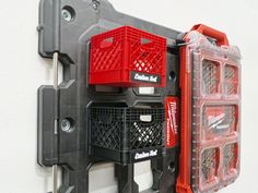 a wall mounted storage rack with three red baskets on it's sides and two black plastic bins attached to the back