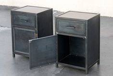 two black metal nightstands with one open and the other closed, sitting on concrete