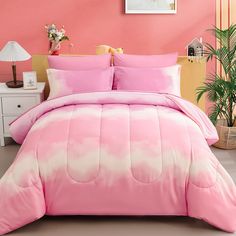 a pink and white comforter set with pillows on the bed in front of a pink wall