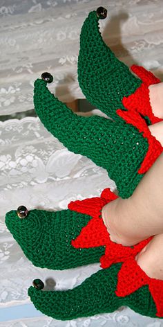 someone is wearing crocheted christmas slippers with red and green bows on them