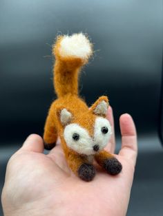 a hand holding a tiny stuffed animal in it's left hand with the tail up