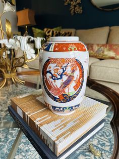 a vase sitting on top of a stack of books in front of a couch and coffee table