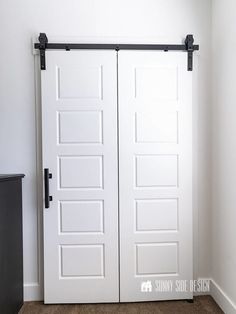 two white doors with black handles in a room