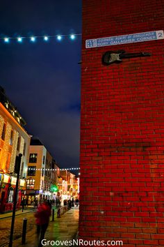 a red brick wall with a street sign on it and people walking down the sidewalk