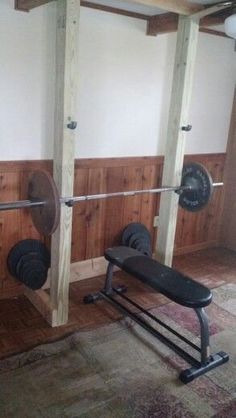 an empty gym room with two squat benches and barbells in the wall behind it