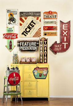 a yellow cabinet with coca - cola signs on the wall next to two stools