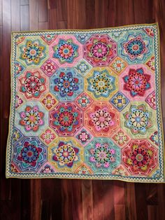 a multicolored crocheted blanket on a wooden floor