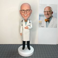 a doctor bobble head next to a photo of an older man in a white lab coat