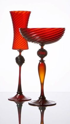 two red glass goblets sitting on top of each other in front of a white background