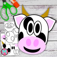 a cow cut out next to scissors and other crafting supplies on a white wooden surface