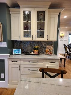 a kitchen with white cabinets and marble counter tops, along with a dining room table