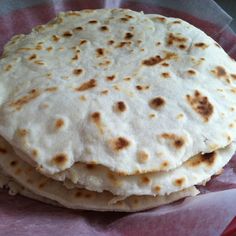 three flat breads stacked on top of each other in a wrapper with pink tissue paper