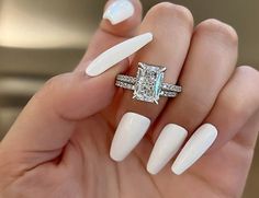 a woman's hand with some white nails and a ring on top of it