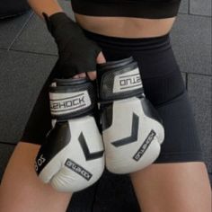 a woman wearing white and black boxing gloves with the words shock written on her hands