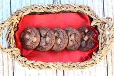 chocolate cookies sitting in a basket on top of a wooden table next to a red napkin