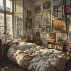 an unmade bed with many pictures on the wall