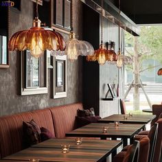 an empty restaurant with many tables and chairs in front of the windows, along with hanging lights