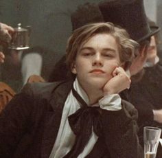 a young man wearing a top hat and bow tie sitting at a table with other people