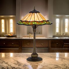 a stained glass lamp sitting on top of a marble countertop in a large kitchen