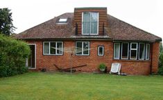 a red brick house with green grass and bushes