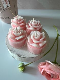 three pink roses sitting on top of a table next to a bottle and some flowers