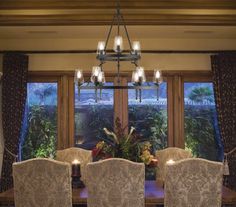 a chandelier hangs over a dining room table with four chairs in front of it