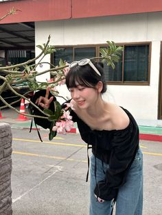 a woman standing next to a tree with pink flowers