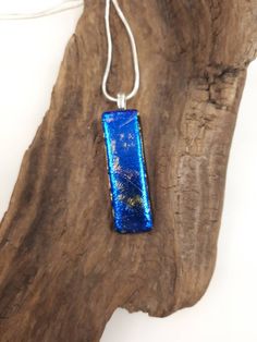 a piece of blue glass sitting on top of a wooden tree branch with a white cord