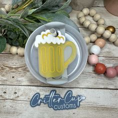 a beer mug shaped cookie sitting on top of a plate next to beads and greenery