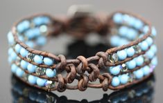 a close up of a bracelet on a black surface with blue beads and brown leather